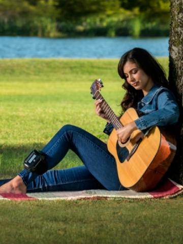 Woman playing guitar wearing physiostim device